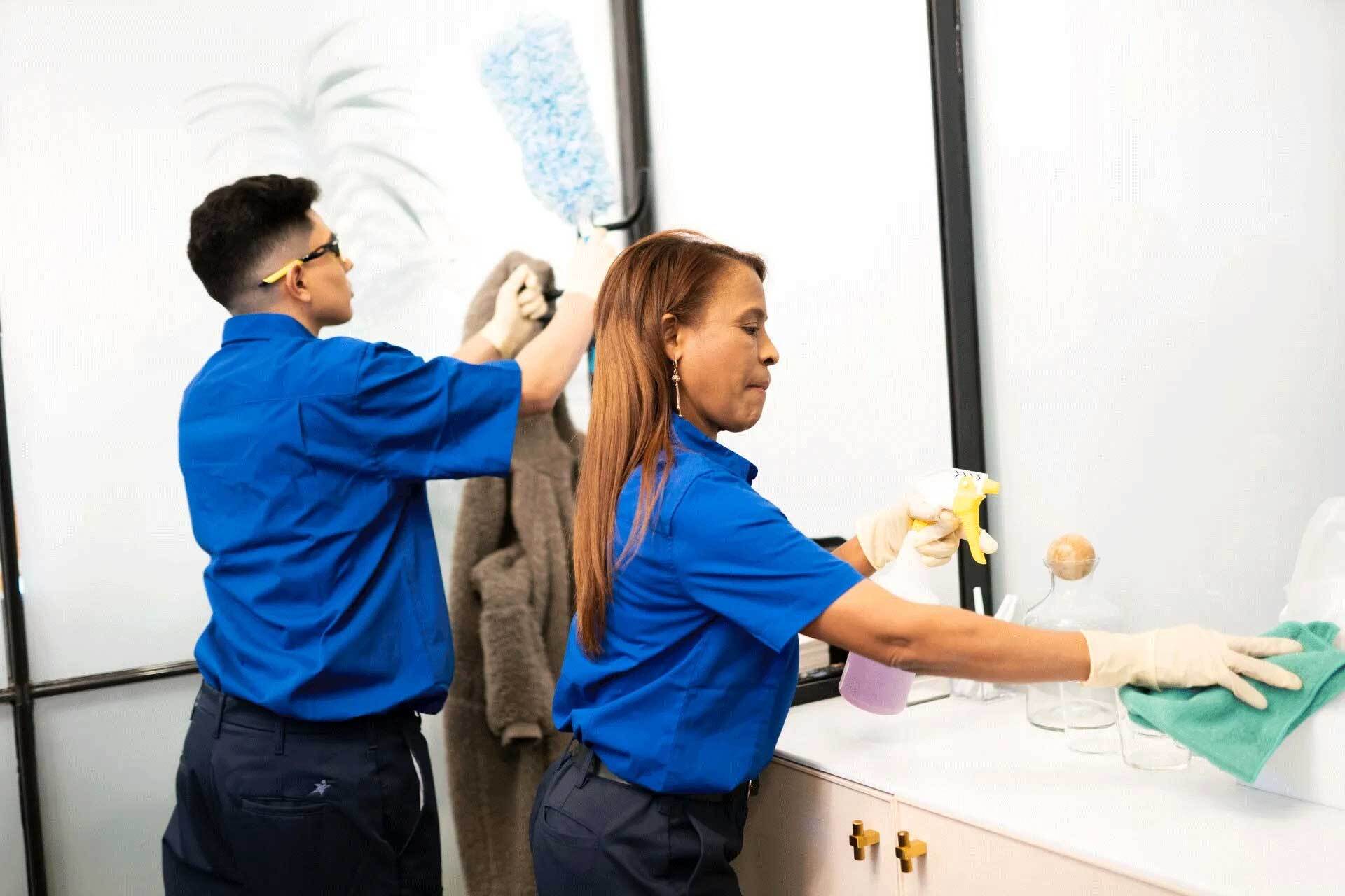 a man and a woman are cleaning a bathroom .