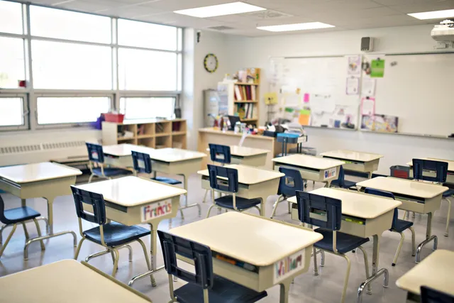 an empty classroom with rows of desks and chairs and a whiteboard .